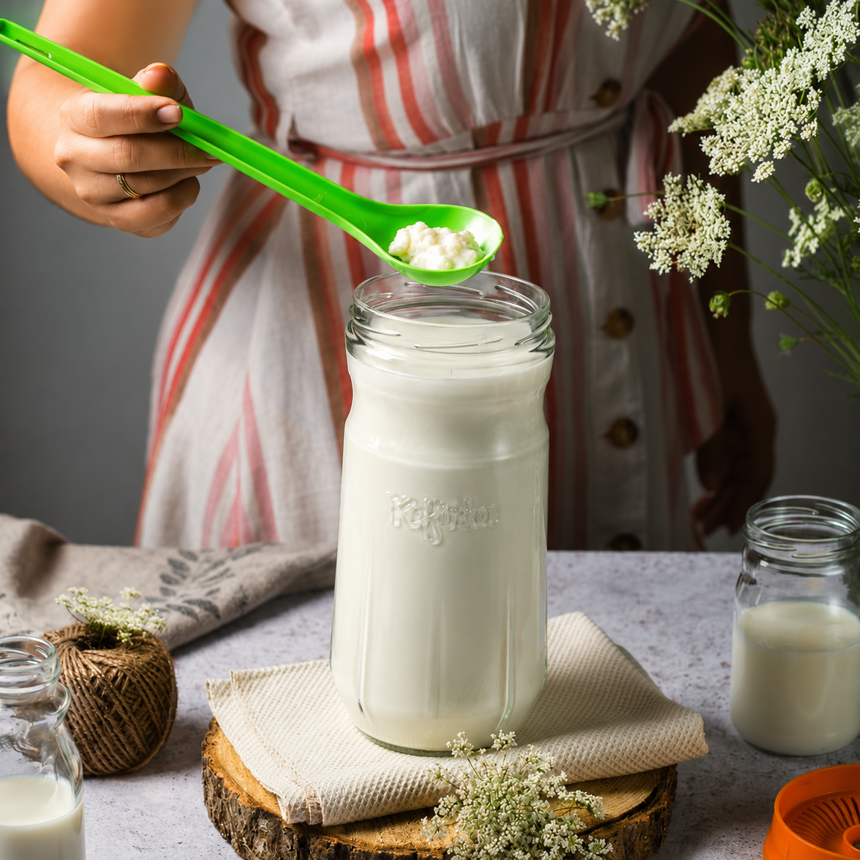 Spoonful of live kefir grains held over a jar of fresh kefir